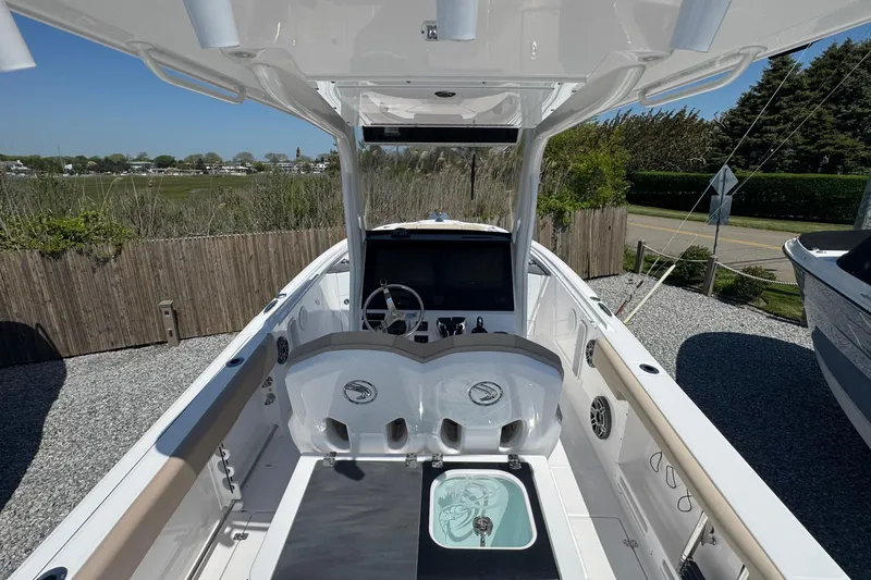 Slide: The Image of 2026 Edgewater 262CC boat interior with modern helm and seating, parked outdoors. - 18