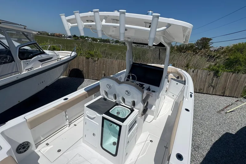 Slide: The Image of 2026 Edgewater 262CC boat interior with helm, seating, and storage, docked outdoors. - 23