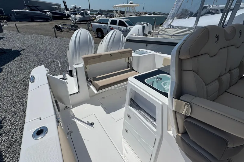 Slide: The Image of 2026 Edgewater 262CC boat interior with seating, storage, and dual outboard motors at a marina. - 24