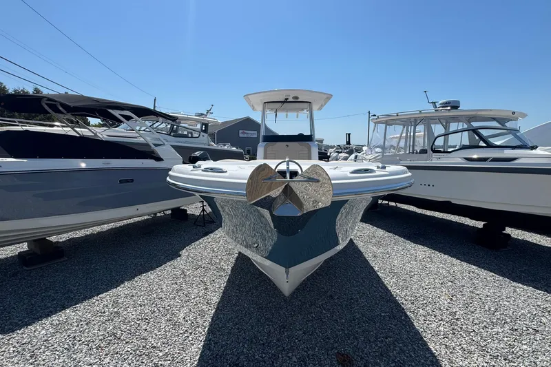Slide: The Image of 2026 Edgewater 262CC boat displayed between two other boats on gravel lot. - 3