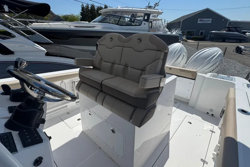 Slide: The Image of 2026 Edgewater 262CC boat interior with dual seats and steering wheel, docked outdoors. - 33