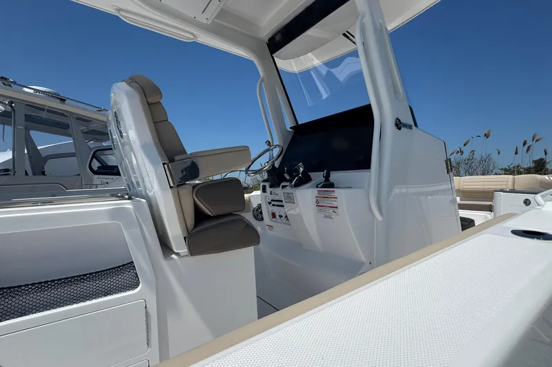 Slide: The Image of 2026 Edgewater 262CC boat interior with helm and seating, under clear blue sky. - 35