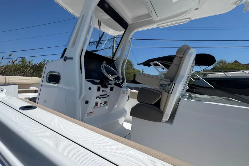 Slide: The Image of 2026 Edgewater 262CC boat interior with steering console and seating under clear blue sky. - 37