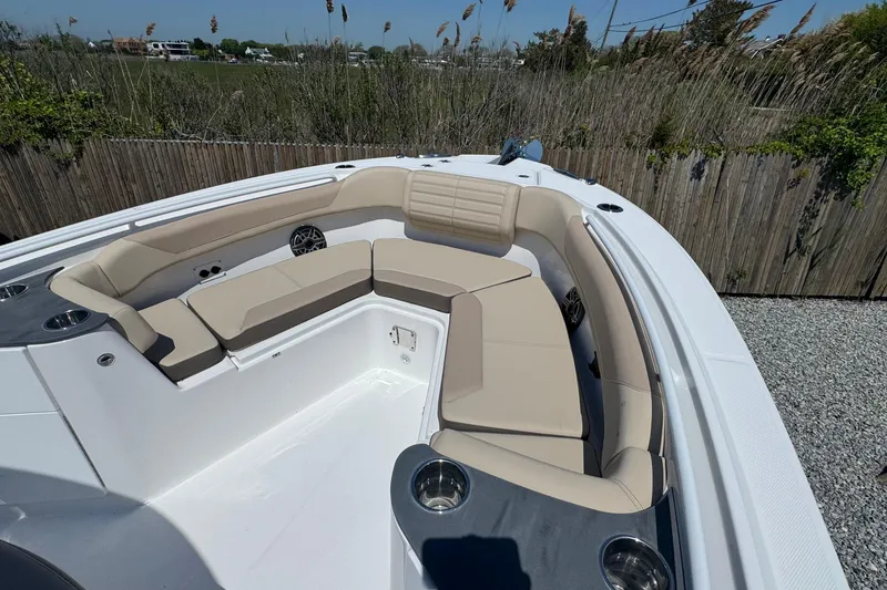 Slide: The Image of 2026 Edgewater 262CC boat with beige seating and cup holders, parked outdoors. - 42