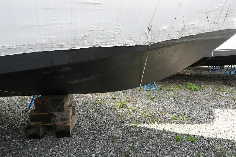 Slide: The Image of 2000 Carver 350 Mariner boat hull on blocks, gravel ground, covered in white tarp. - 49