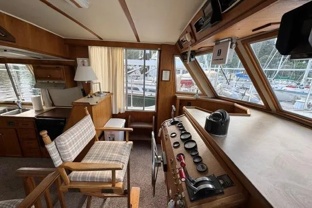 Slide: The Image of 1984 Uniflite YACHTHOME interior with helm, wooden cabinetry, and marina view. - 14