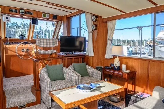 Slide: The Image of 1984 Uniflite YACHTHOME interior with helm, seating, and large windows overlooking marina. - 15