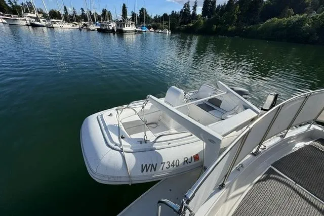 Slide: The Image of 1984 Uniflite YACHTHOME with inflatable boat docked on calm water. - 2