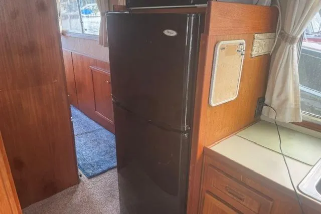 Slide: The Image of Interior of 1984 Uniflite YACHTHOME with black refrigerator and wooden cabinetry. - 20