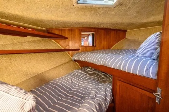 Slide: The Image of 1984 Uniflite YACHTHOME cabin with striped bedding and wooden interior. - 26
