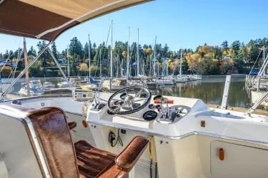 Slide: The Image of 1984 Uniflite YACHTHOME helm with marina view, featuring steering wheel and controls. - 6