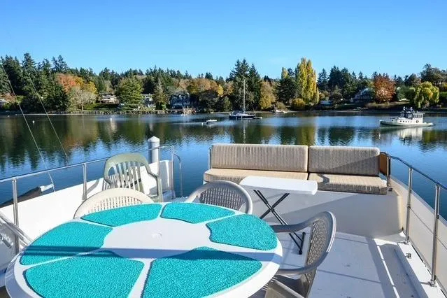 Slide: The Image of 1984 Uniflite YACHTHOME on serene lake, featuring outdoor seating and scenic views. - 7