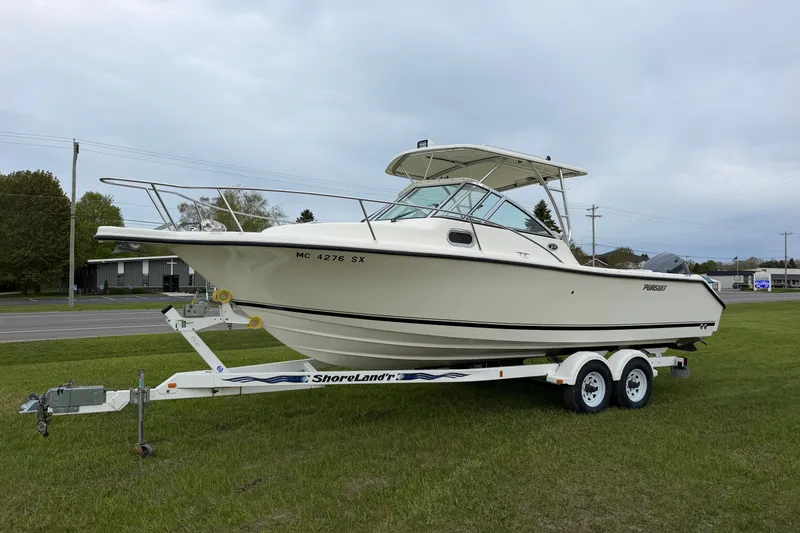 The Image of 2006 Pursuit 2570 Offshore boat on ShoreLand'r trailer, parked on grass. - 0