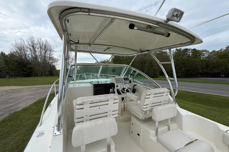 Slide: The Image of 2006 Pursuit 2570 Offshore boat interior with helm and seating, parked on grass. - 16