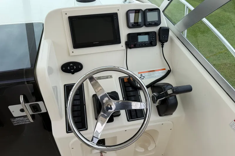 Slide: The Image of Helm of 2006 Pursuit 2570 Offshore boat with steering wheel and navigation controls. - 18