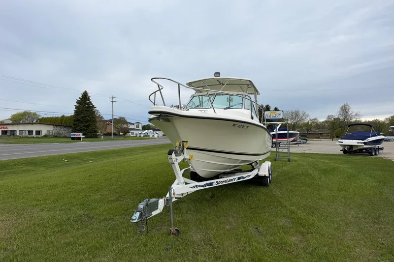 Slide: The Image of 2006 Pursuit 2570 Offshore boat on trailer, parked on grass near road. - 2