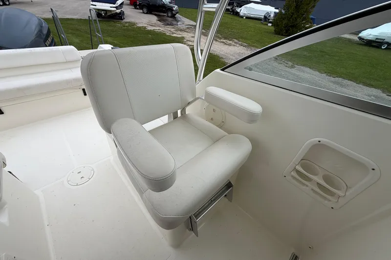 Slide: The Image of Captain's chair on 2006 Pursuit 2570 Offshore boat, featuring white upholstery and armrests. - 22