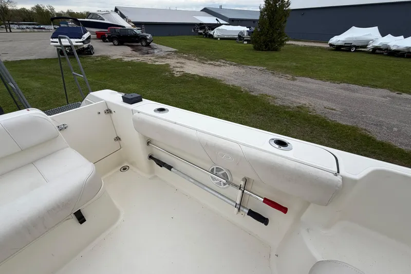 Slide: The Image of 2006 Pursuit 2570 Offshore boat interior with seating and storage, parked outdoors. - 28