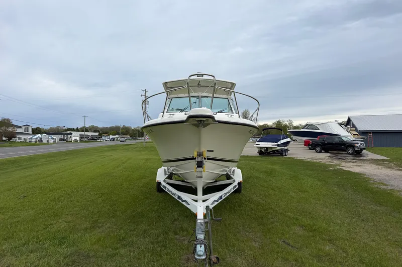 Slide: The Image of 2006 Pursuit 2570 Offshore boat on trailer, parked on grassy area under cloudy sky. - 3