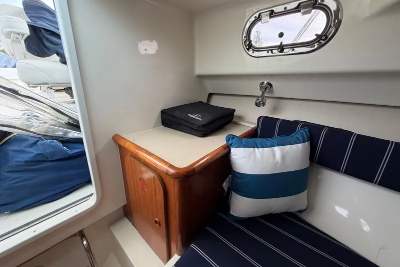 Slide: The Image of Interior of 2006 Pursuit 2570 Offshore boat with striped cushions and wooden cabinet. - 31