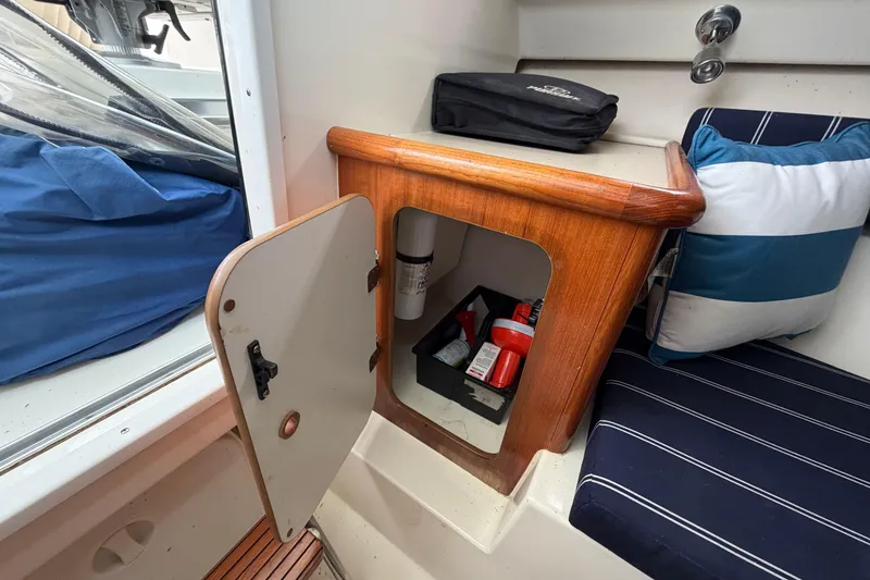 Slide: The Image of 2006 Pursuit 2570 Offshore boat interior with open storage compartment and striped seating. - 33
