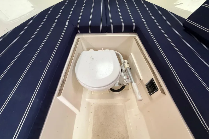 Slide: The Image of 2006 Pursuit 2570 Offshore boat interior with marine toilet and striped cushions. - 34
