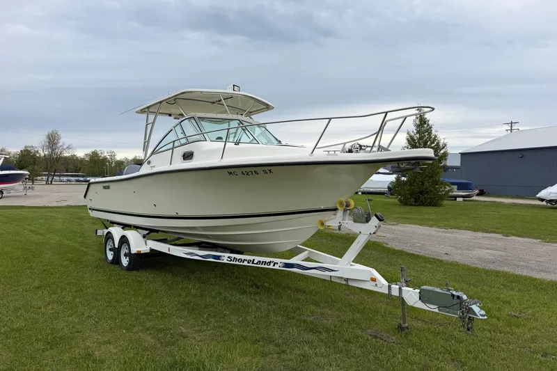 Slide: The Image of 2006 Pursuit 2570 Offshore boat on trailer, parked on grass near a building. - 4