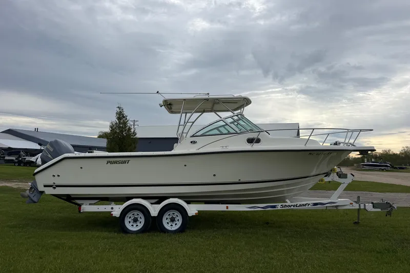 Slide: The Image of 2006 Pursuit 2570 Offshore boat on trailer, parked on grass under cloudy sky. - 5