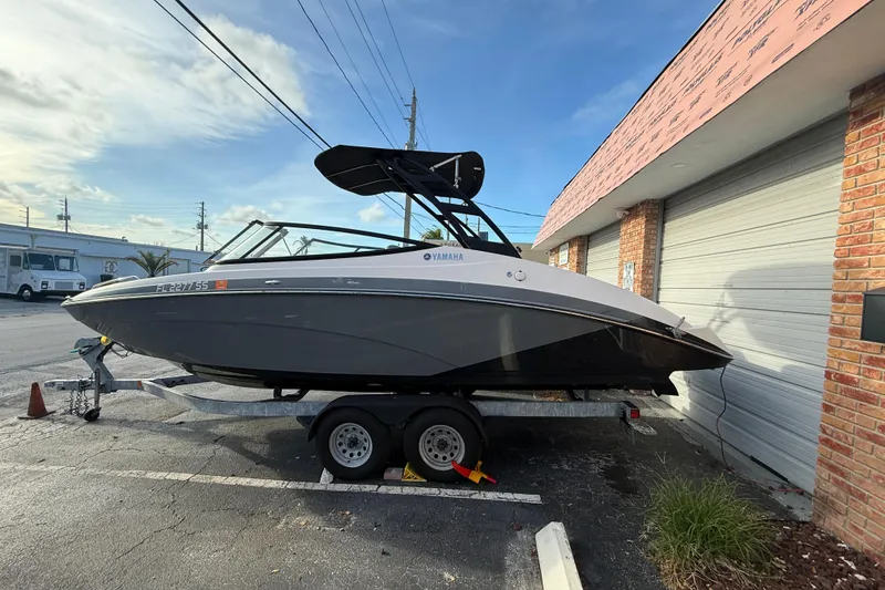 Slide: The Image of 2020 Yamaha AR230 boat on trailer, parked outside a building. - 2