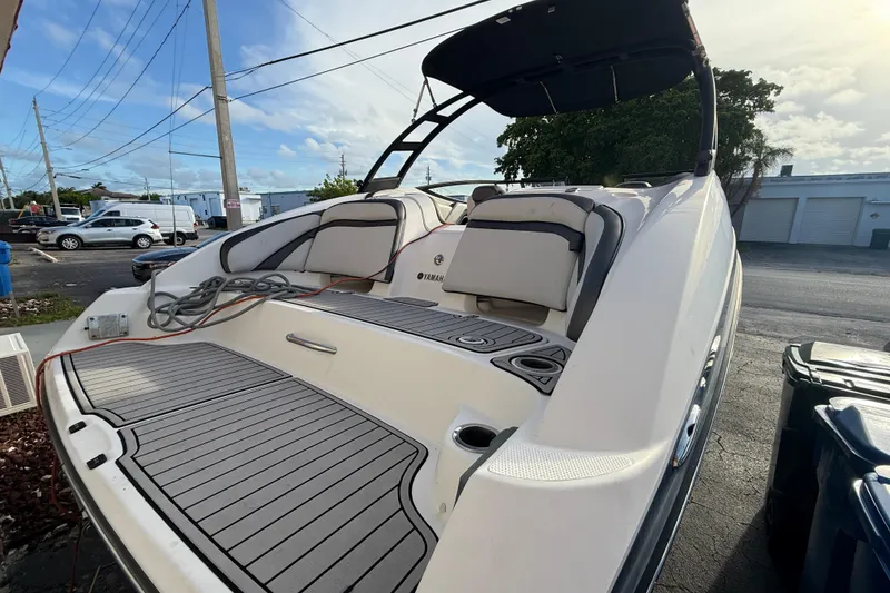Slide: The Image of 2020 Yamaha Boats AR230 with spacious deck and seating, parked outdoors. - 5