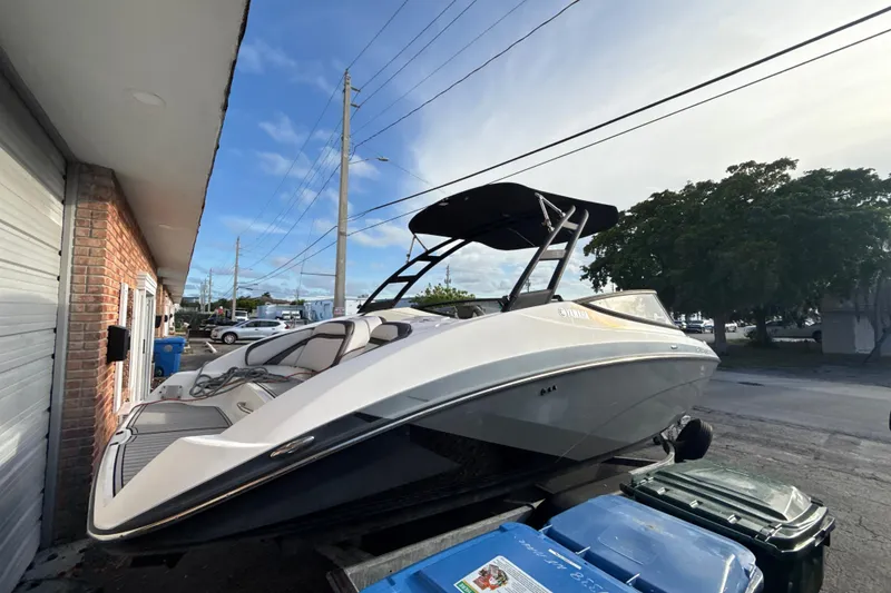 Slide: The Image of 2020 Yamaha AR230 boat parked outdoors near a brick building. - 6