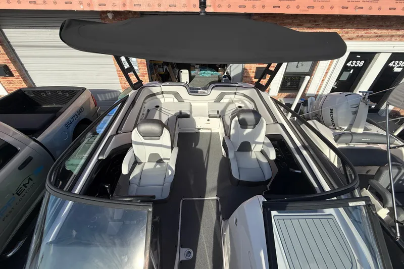 Slide: The Image of 2020 Yamaha Boats AR230 interior with seating and canopy, parked near a building. - 9