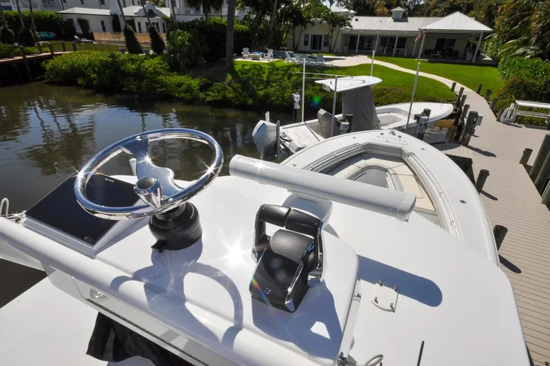 Slide: The Image of 2011 Yellowfin 39 Offshore boat docked, featuring steering wheel and controls, with waterfront view. - 22