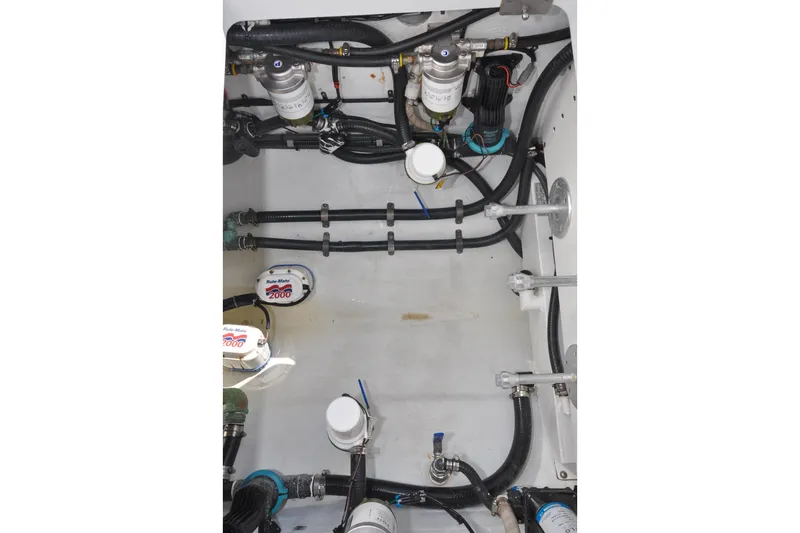 Slide: The Image of Engine compartment of a 2011 Yellowfin 39 Offshore boat, showcasing pumps and hoses. - 39