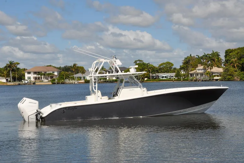 Slide: The Image of 2011 Yellowfin 39 Offshore boat on calm water, with waterfront homes in the background. - 43