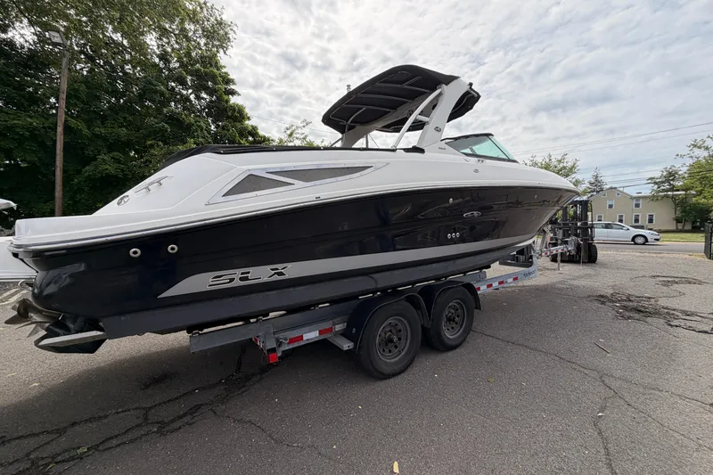 The Image of 2011 Sea Ray 300 SLX boat on trailer, parked outdoors, under cloudy sky. - 0