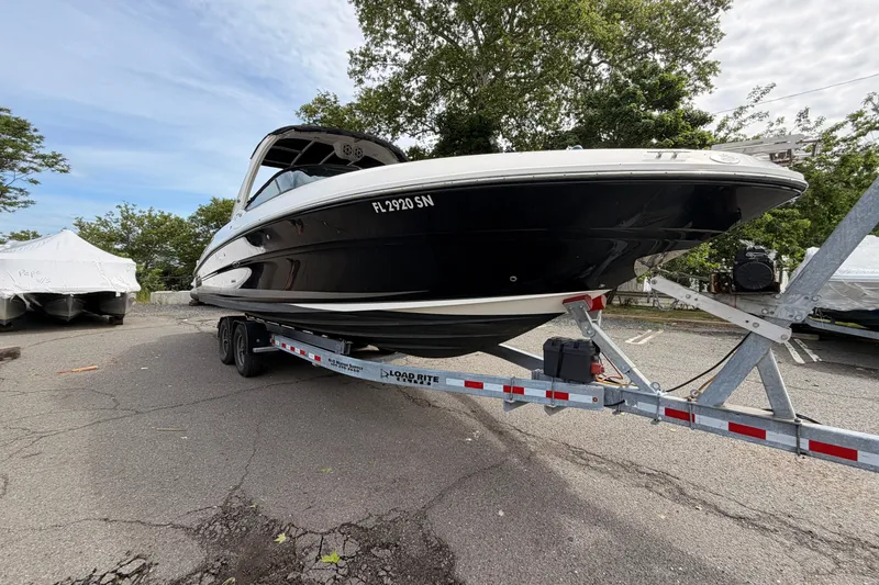 Slide: The Image of 2011 Sea Ray 300 SLX boat on trailer, parked outdoors with trees in background. - 1