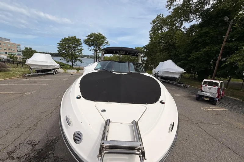 Slide: The Image of 2011 Sea Ray 300 SLX boat parked on asphalt near covered boats and trees. - 2
