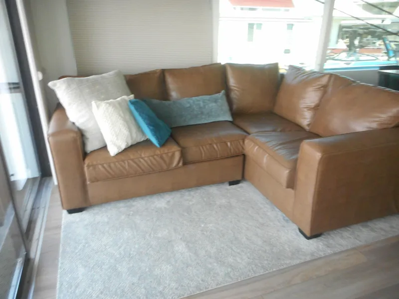 Slide: The Image of Brown leather sectional sofa with assorted pillows on a light rug, Adonia Obsession Trip #12, 2021. - 23