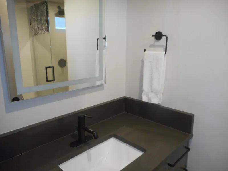 Slide: The Image of Modern bathroom with sleek black countertop, white sink, and towel rack. Adonia Obsession Trip #12, 2021. - 8