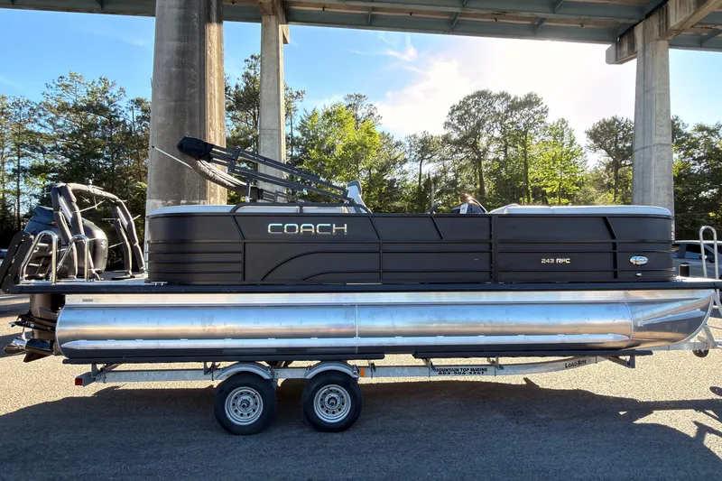 The Image of 2026 Coach 243 RFC pontoon boat on trailer under bridge, sunny day. - 0
