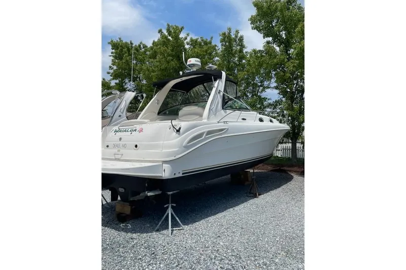 Slide: The Image of 2000 Sea Ray 340 Sundancer boat on stands, surrounded by trees and gravel. - 2