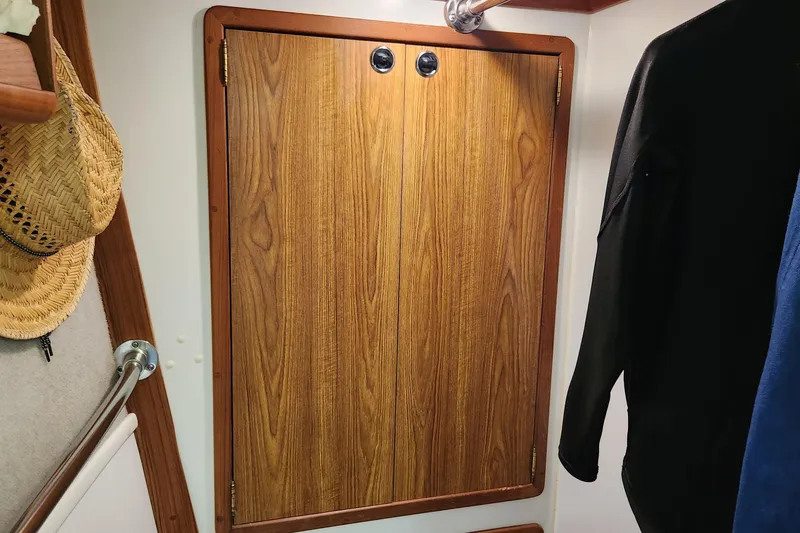 Slide: The Image of Wooden cabinet door inside 2003 Endeavour 44 TrawlerCat, with hanging clothes and straw hat. - 37