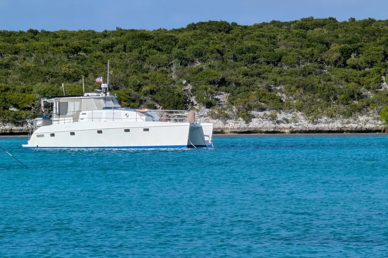Slide: The Image of Endeavour 44 TrawlerCat 2003 cruising in clear blue waters near lush green shoreline. - 4