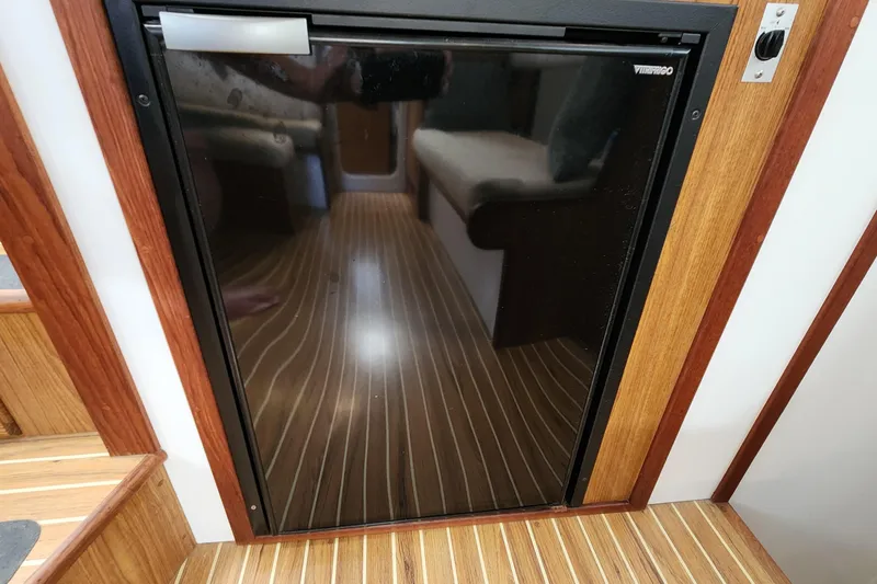 Slide: The Image of Compact fridge on 2003 Endeavour 44 TrawlerCat, featuring sleek wood paneling and striped flooring. - 51