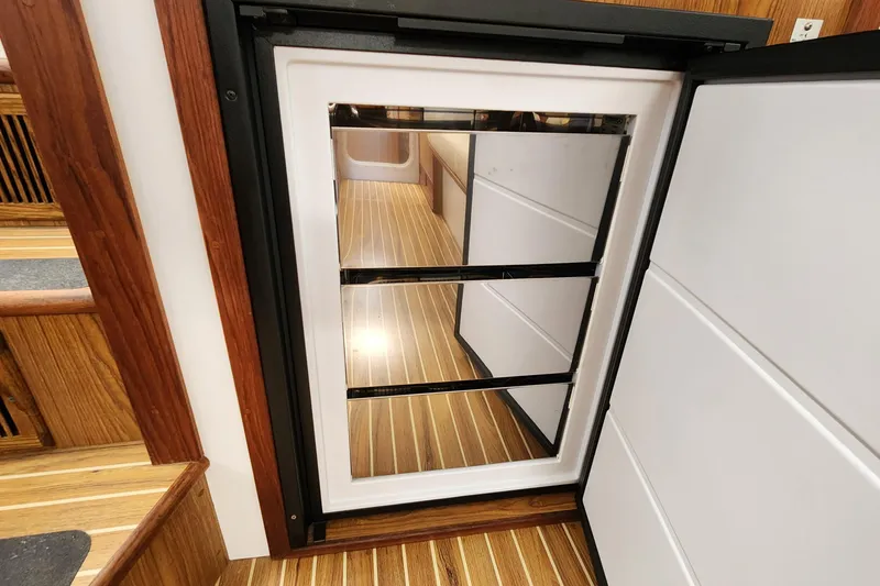 Slide: The Image of Open refrigerator door on 2003 Endeavour 44 TrawlerCat, showcasing wooden interior flooring. - 52