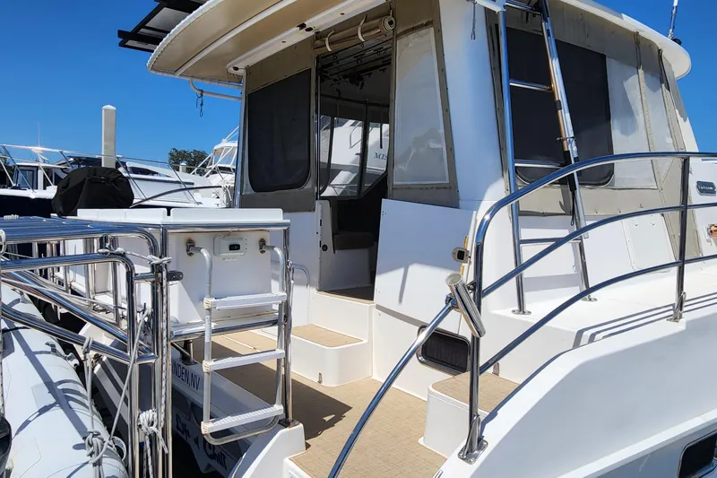 Slide: The Image of 2003 Endeavour 44 TrawlerCat boat with stainless steel railings and ladder, docked under clear skies. - 6