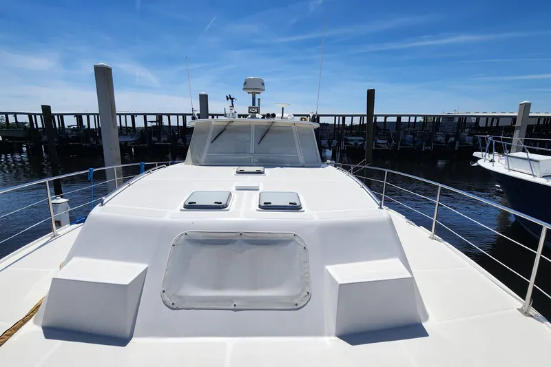 Slide: The Image of 2003 Endeavour 44 TrawlerCat docked, showcasing spacious deck and sleek design under clear skies. - 63