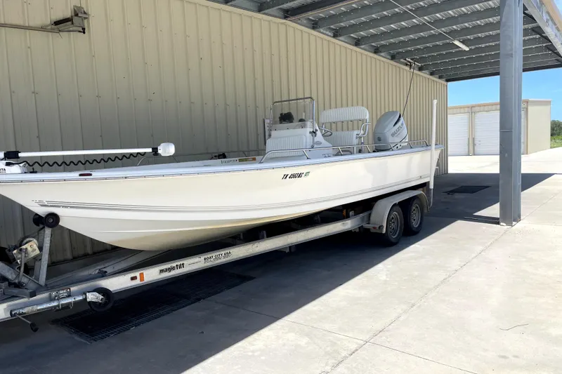 The Image of 2005 Sea Pro SV2400CC Bay Boat on trailer under metal canopy. - 0