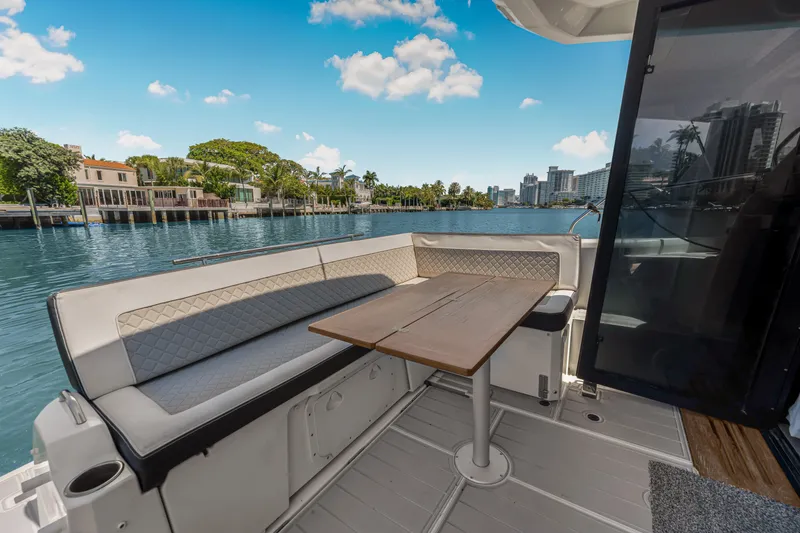Slide: The Image of 2020 Jeanneau NC 37 boat deck with seating and table, overlooking waterfront homes. - 19